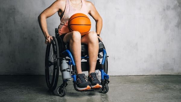A man in a wheelchair with a basketball in his lap.
