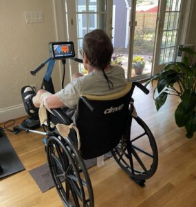 Image of a man in a black wheel chair wearing a grey shirt.